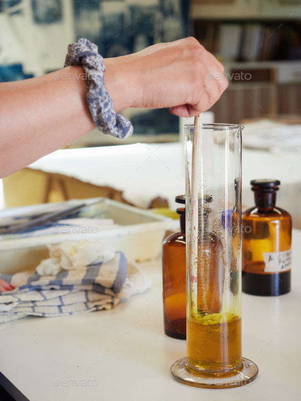 hand mixing amber colored chemical liquid in a glass test tube in